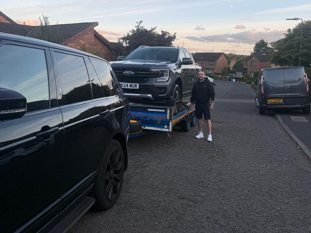 Nationwide Vehicle Transportation driver beside a loaded car trailer