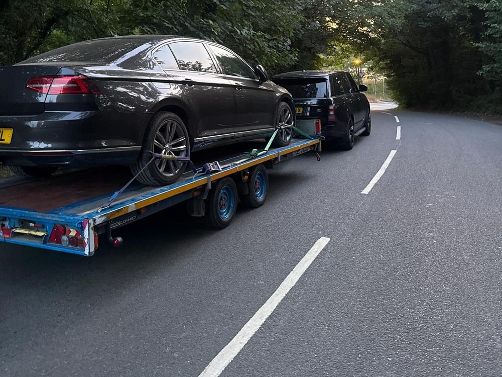 Volkswagen Passat strapped onto a trailer on a country road